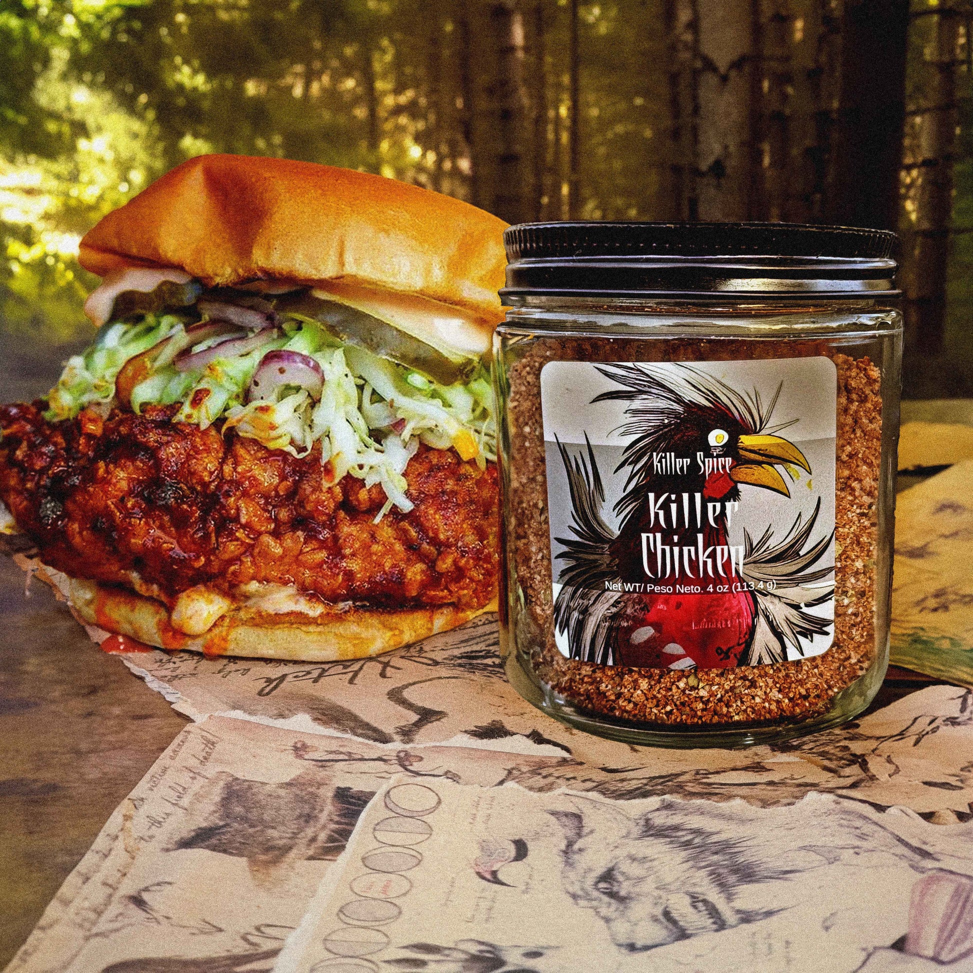 Killer Chicken seasoning jar next to spicy chicken sandwich with coleslaw on rustic wooden surface with forest background