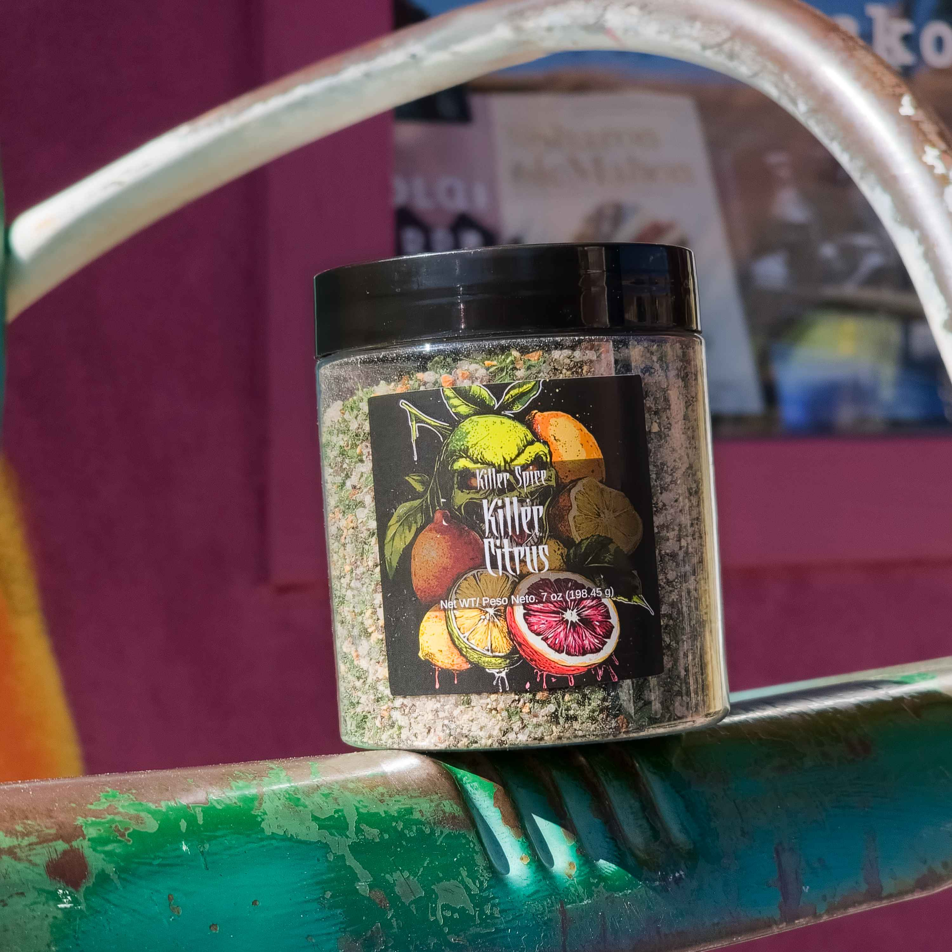 Clear jar of Killer Citrus spice blend with colorful citrus fruit label against purple and teal background