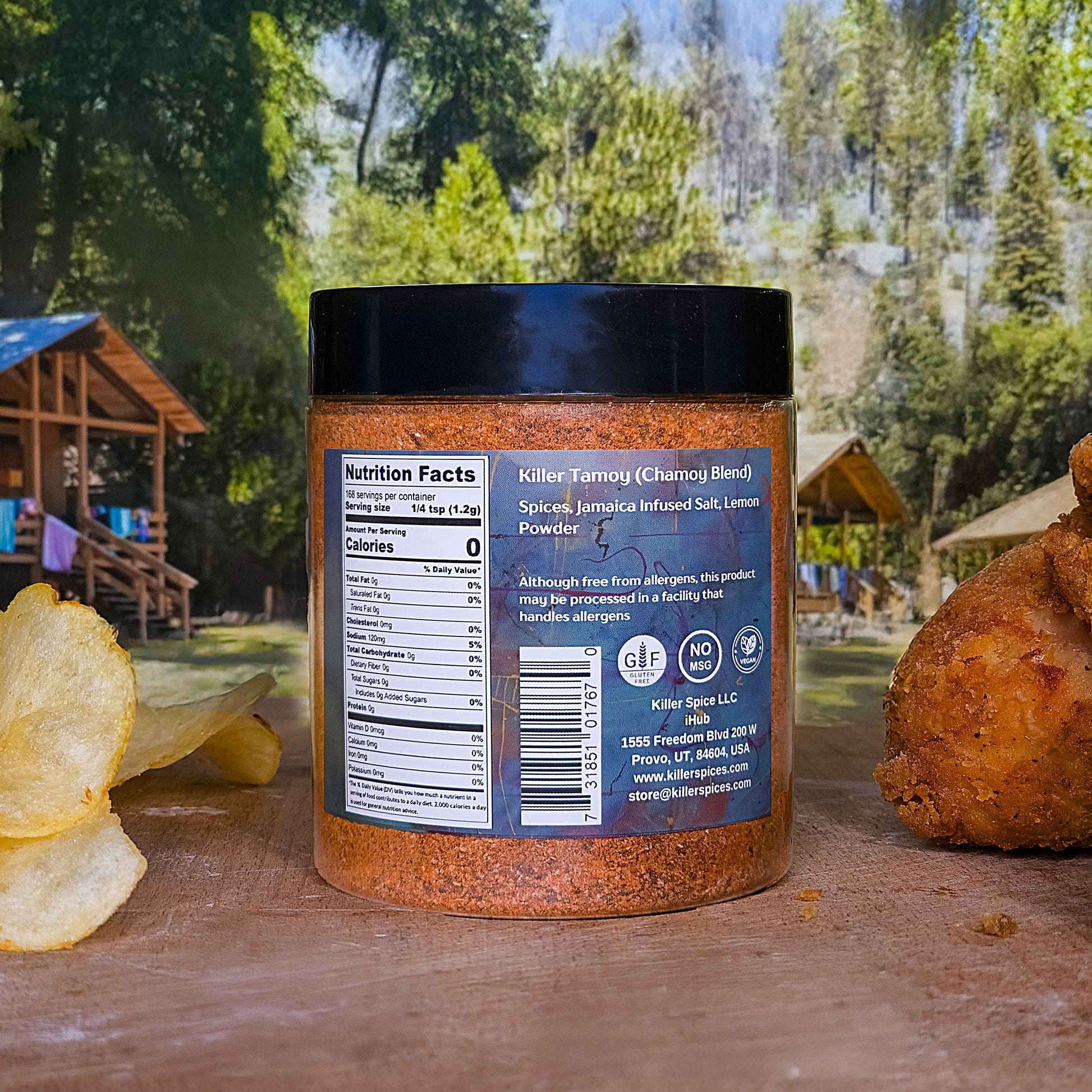 A jar of Killer Tamoy chamoy seasoning blend displayed with chips, showing nutrition facts label against a forest backdrop