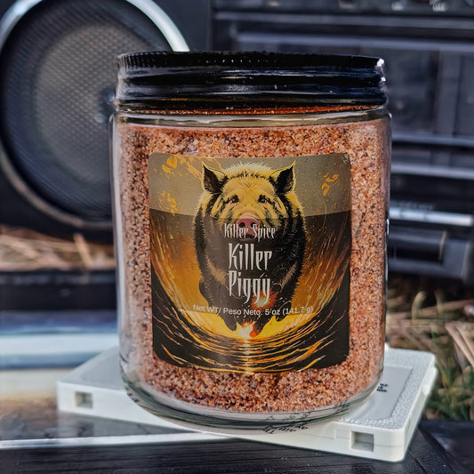 A jar of "Killer Piggy (Smoky BBQ Spice)" barbecue seasoning with a graphic of a pig on the label, displayed outdoors.