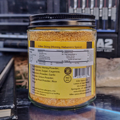 A jar of Killer Sting honey with habanero and cayenne pepper spice blend on a shelf, displaying the ingredients and branding.