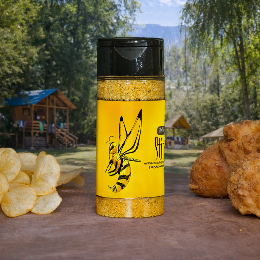 Yellow seasoning container with black lid on a wooden surface outdoors, with trees and mountains in the background.