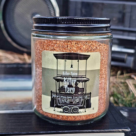 A jar of Killer Spice brand Killer Taco seasoning with cumin on an outdoor surface.