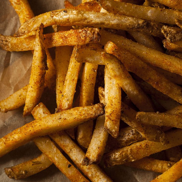 Stack of golden brown fries on brown paper