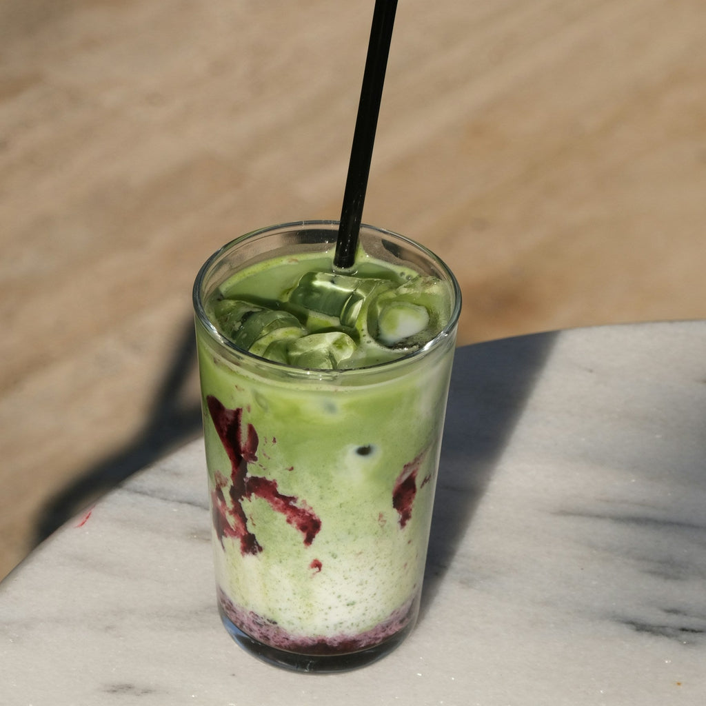 Green smoothie in a glass with a straw on a marble surface