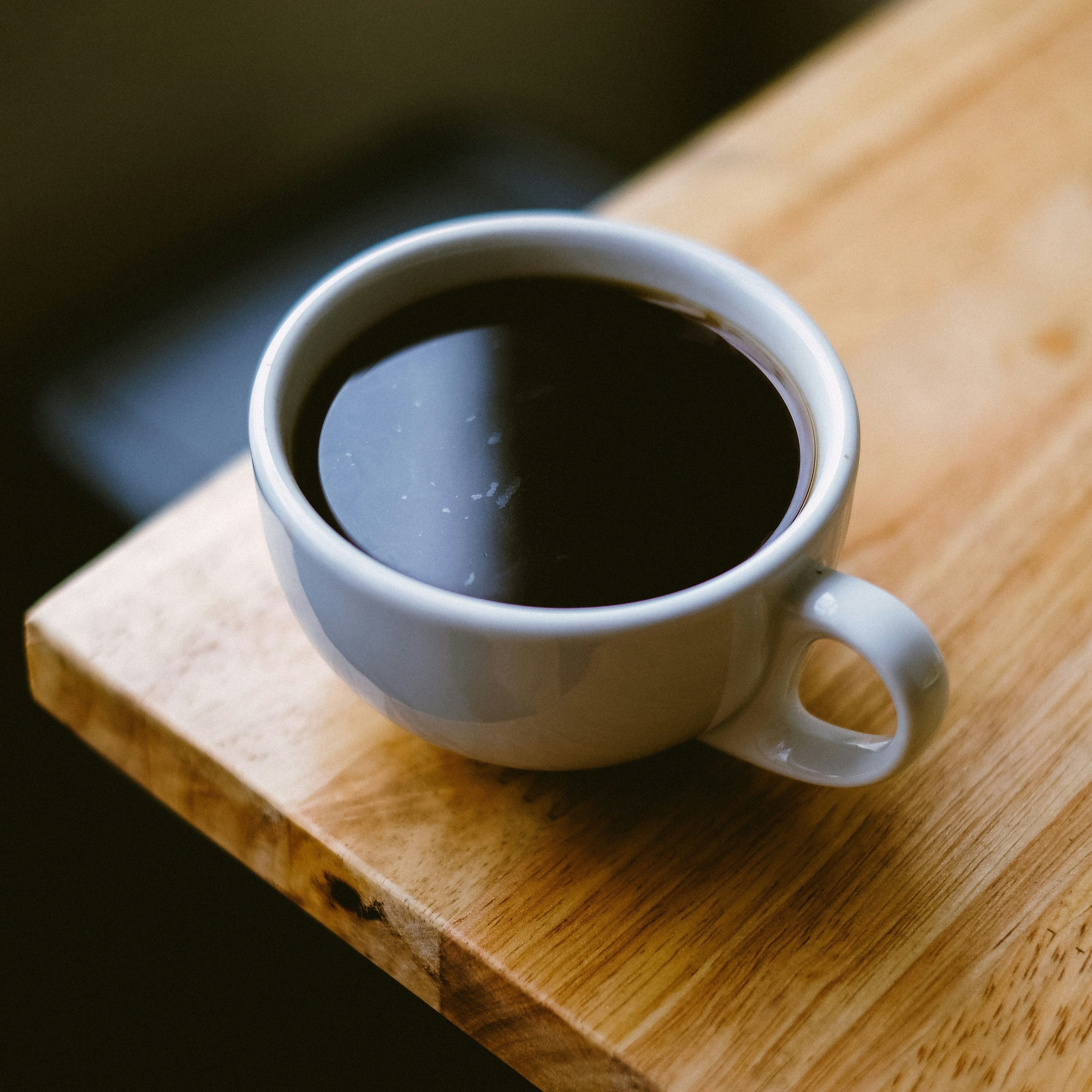 White mug with dark liquid on a wooden surface