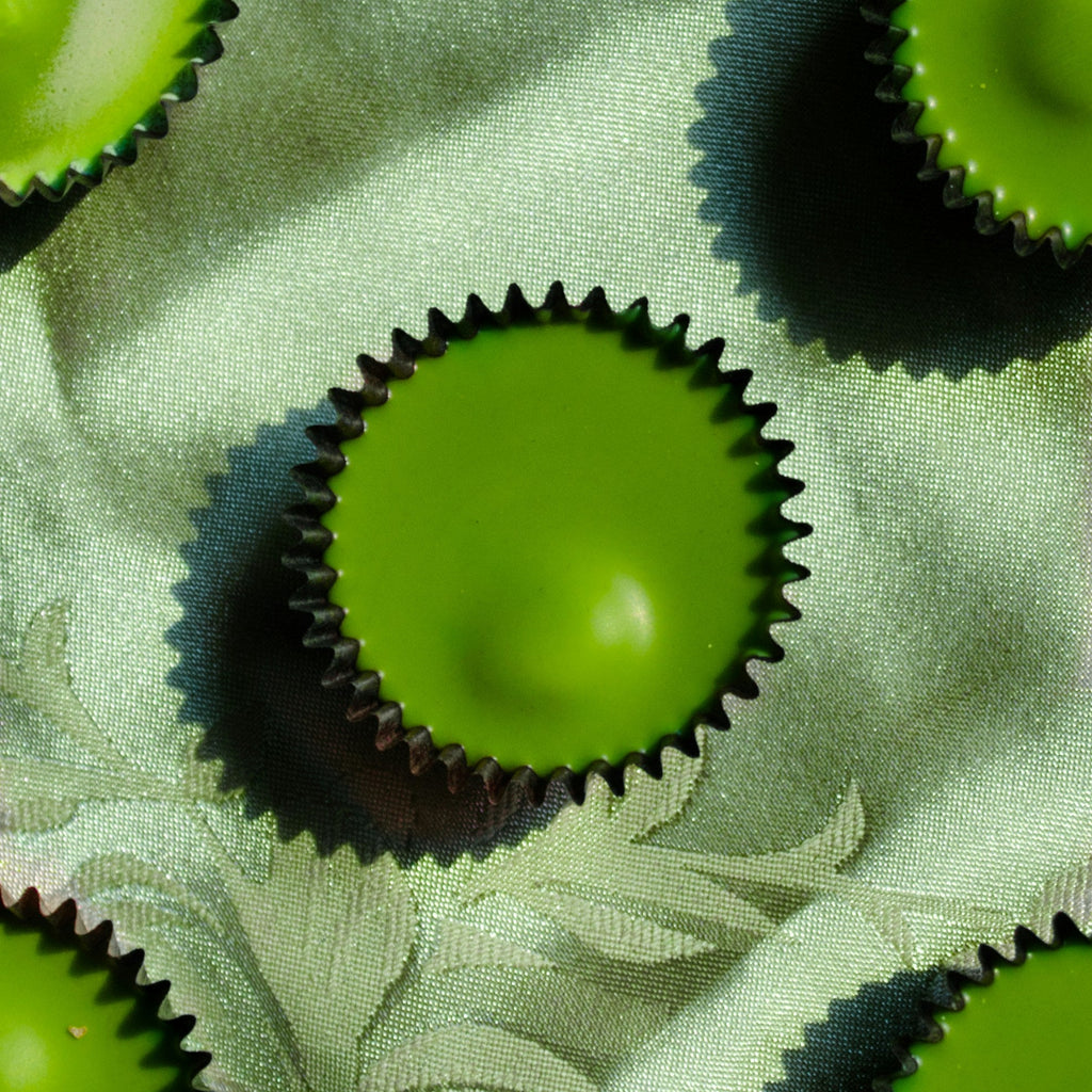Green chocolate cups with dark brown wrappers on a green fabric background