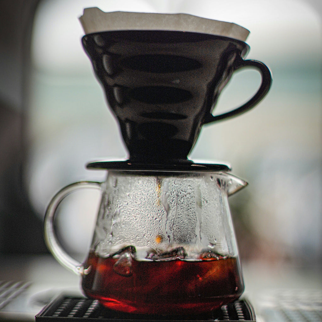 Coffee brewing process with a glass carafe and filter on a blurred background