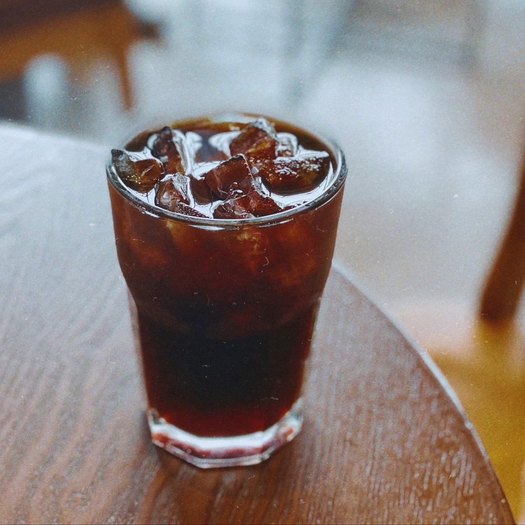 Glass of iced coffee on a wooden table with a blurred background