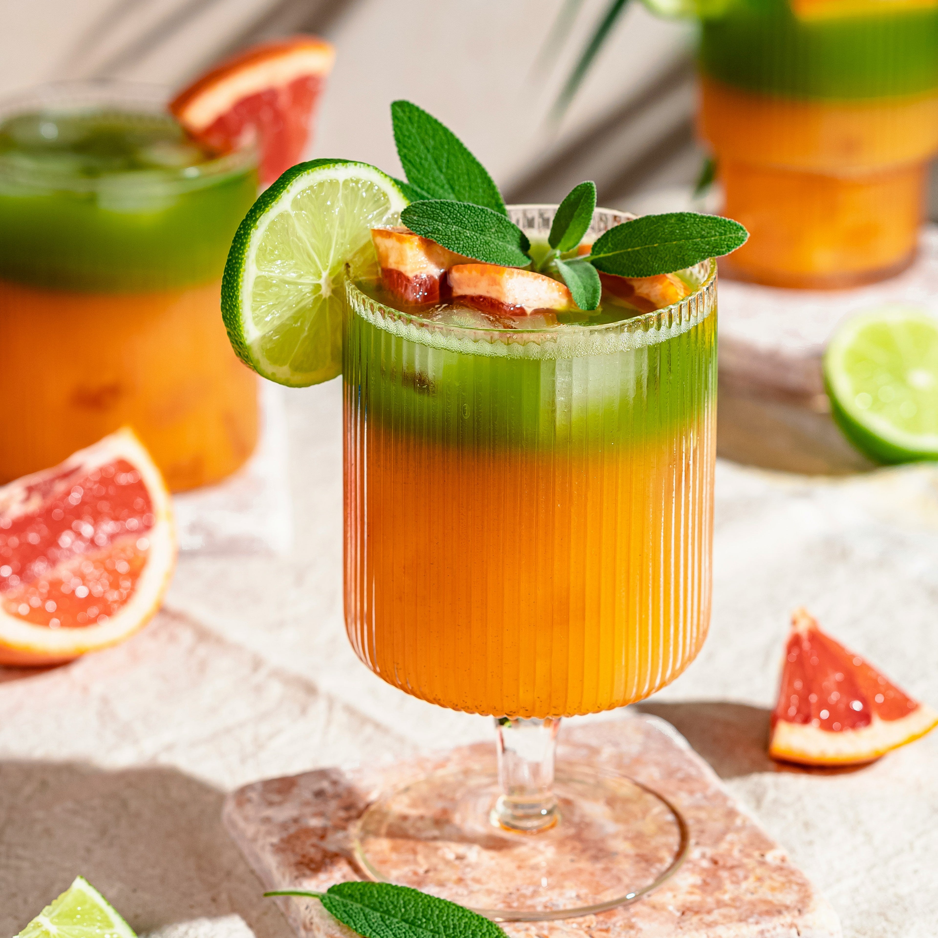 Colorful cocktails with lime and grapefruit slices on a textured surface